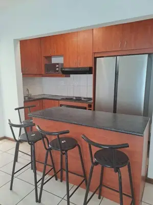 a kitchen with a counter with four chairs and a refrigerator at Azzure Apartments 3 sleeper Strand in Strand