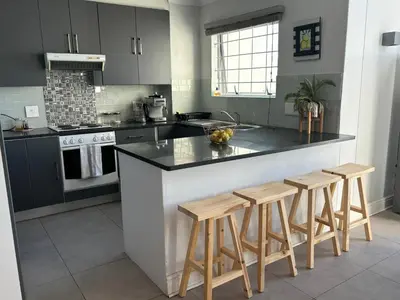 a kitchen with a counter and stools in it at Serene loft apartment in Cape Town