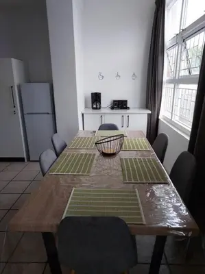 a dining room table with chairs and a kitchen with a tableablish at Azzure Apartments 4 sleeper Strand in Strand