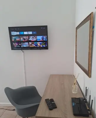 a desk with a chair and a television on a wall at Azzure Apartments 4 sleeper Strand in Strand