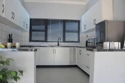a white kitchen with white cabinets and a sink at Harbour View in Cape Town