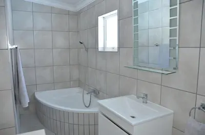 a white bathroom with a tub and a sink at Harbour View in Cape Town