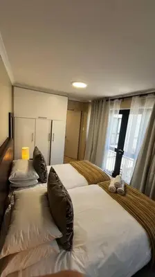 a hotel room with two beds and a window at Cosy Central Apartment - By ARPA Hospitalities in Stellenbosch