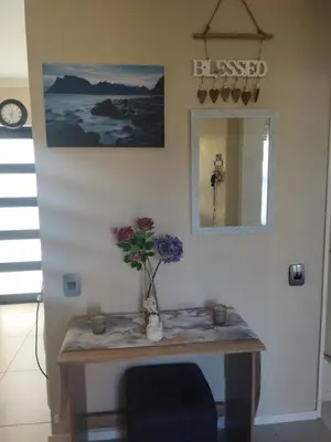 a room with a table with a vase of flowers on it at 21 Pin Oak Guest House in Cape Town