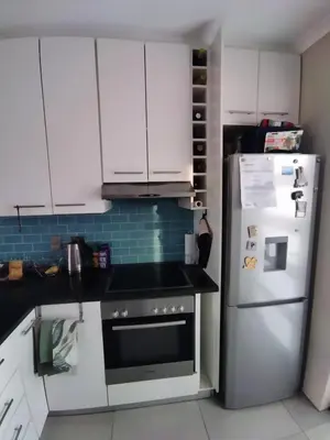 a kitchen with white cabinets and a refrigerator at 21 Pin Oak Guest House in Cape Town