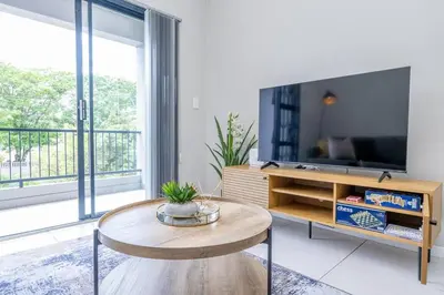 a living room with a table and a tv at Cozy Apartment in Brackenfell, Cape Town, ZA in Brackenfell