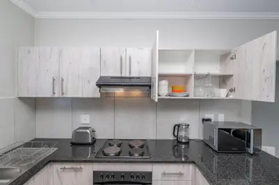 a kitchen with white cabinets and a stove top oven at Cozy Apartment in Brackenfell, Cape Town, ZA in Brackenfell