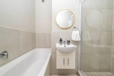 a bathroom with a tub and a sink and a mirror at Cozy Apartment in Brackenfell, Cape Town, ZA in Brackenfell