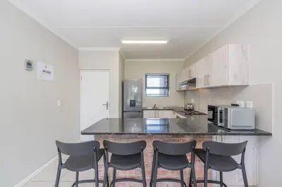 a kitchen with a counter with four chairs in it at Cozy Apartment in Brackenfell, Cape Town, ZA in Brackenfell