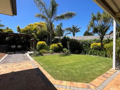a backyard with a lawn and palm trees at 7Pillars Villa Grenache in Durbanville