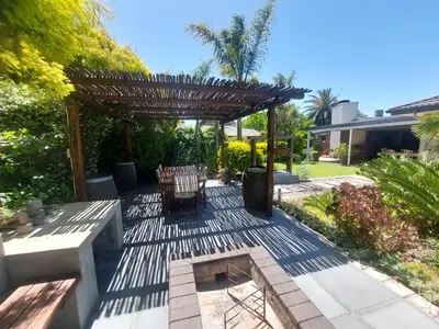 a patio with a pergola and a table and bench at 7Pillars Villa Grenache in Durbanville