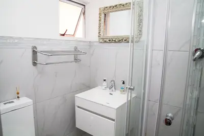 a white bathroom with a toilet and a shower at Luxurious Flatlet in the heart of Mowbray in Cape Town