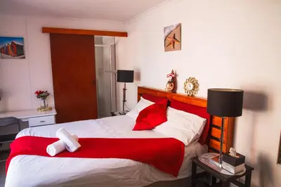 a bedroom with a large bed with red and white pillows at Luxurious Flatlet in the heart of Mowbray in Cape Town