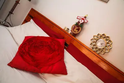 a red pillow sitting on top of a bed with a clock at Luxurious Flatlet in the heart of Mowbray in Cape Town