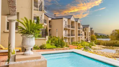 a villa with a swimming pool in front of a building at W-Collection Franschhoek L'Ermitage Villas in Franschhoek