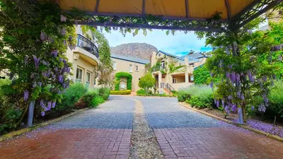 a cobblestone street with purple wisteria on the walls at W-Collection Franschhoek L'Ermitage Villas in Franschhoek