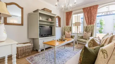 a living room with a tv and a table at W-Collection Franschhoek L'Ermitage Villas in Franschhoek