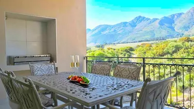 a table with a bowl of fruit on top of a balcony at W-Collection Franschhoek L'Ermitage Villas in Franschhoek