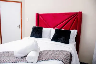a bedroom with a large bed with a red headboard at Comfort on Wrench in Cape Town