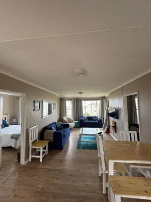 a living room with a blue couch and a bed at Hermanus Beach Club 104 in Hermanus