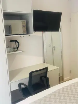 a bedroom with a desk and a chair and a monitor at Private Luxury Room by 29 Holborn in Cape Town