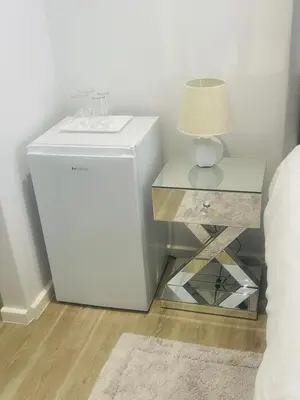 a white refrigerator next to a table with a lamp at Private Luxury Room by 29 Holborn in Cape Town