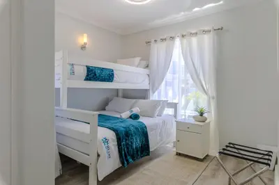 a white bedroom with a bunk bed and a window at Hermanus - Heart of the Sea in Hermanus