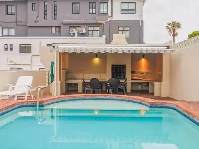 a swimming pool with a table and chairs next to a building at Hermanus - Heart of the Sea in Hermanus