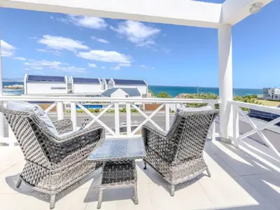 a balcony with two chairs and a view of the ocean at Hermanus - Heart of the Sea in Hermanus