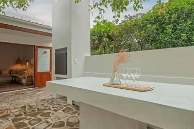 a table with two glasses and a vase on it at Heartwood Cottage in Hermanus