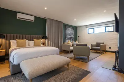 a bedroom with a bed and a living room at Franschhoek Hotel in Franschhoek