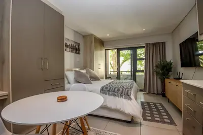 a bedroom with a bed and a white table at 23 On The Den Studio Apartment in Stellenbosch