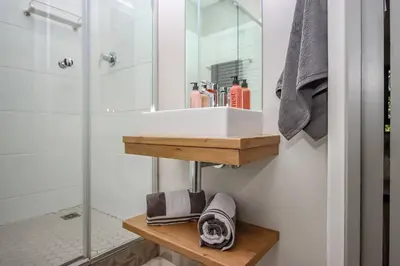 a bathroom with a sink and a glass shower at 23 On The Den Studio Apartment in Stellenbosch