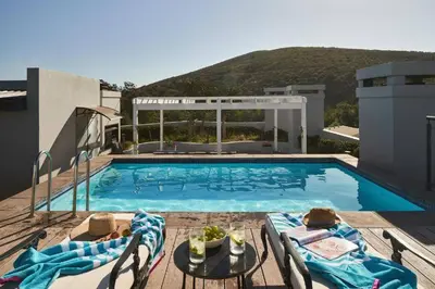 a swimming pool with two chairs and a table on a building at 23 On The Den Studio Apartment in Stellenbosch