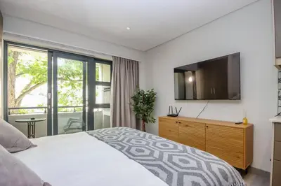 a bedroom with a bed and a flat screen tv at 23 On The Den Studio Apartment in Stellenbosch