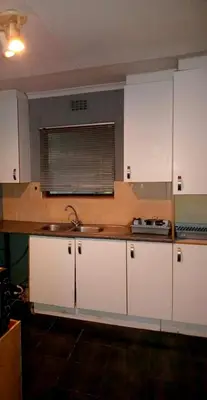 a kitchen with white cabinets and a sink at Highbury Back Packers in Cape Town