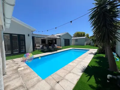 a swimming pool in the backyard of a house with a palm tree at Luxurious 12 sleeper Appaloosa Villa in Cape Town