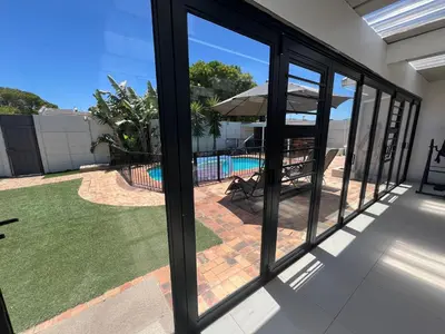 a view of the pool through the windows of a house at Luxurious 12 sleeper Appaloosa Villa in Cape Town