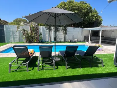 a table and chairs with an umbrella next to a pool at Luxurious 12 sleeper Appaloosa Villa in Cape Town