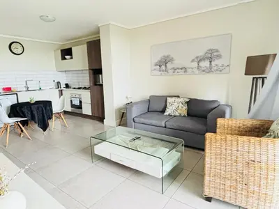 a living room with a couch and a table at 6 sleeper apartment near Canal Walk in Cape Town