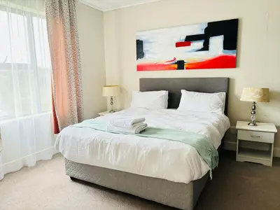 a bedroom with a bed and a painting on the wall at 6 sleeper apartment near Canal Walk in Cape Town
