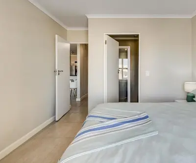 a bedroom with a white bed and a hallway at Beachside Getaway in Cape Town