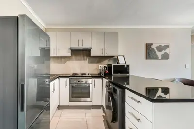 a kitchen with white cabinets and stainless steel appliances at Beachside Getaway in Cape Town