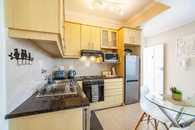 a kitchen with wooden cabinets and a counter top at Coral Breeze Walk to Everything in Cape Town