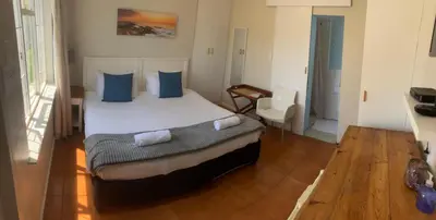 a bedroom with a large bed with blue pillows at Table View Lodge in Cape Town