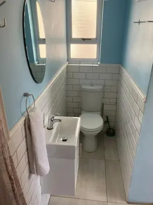 a bathroom with a toilet and a sink and a mirror at Table View Lodge in Cape Town