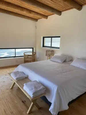 a bedroom with a large white bed with two windows at Villa Sur La Mer in Pringle Bay