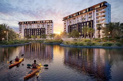 two people in kayaks on a river with two buildings at ParkPlace in Cape Town
