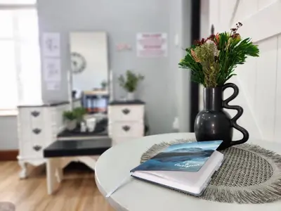 a table with a vase and a book on it at Le Graan Guestroom in Malmesbury