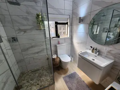 a bathroom with a shower and a sink and a mirror at Le Graan Guestroom in Malmesbury
